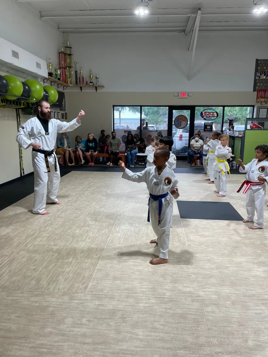 A Force of One instructor leading young students through a technique on the dojang floor